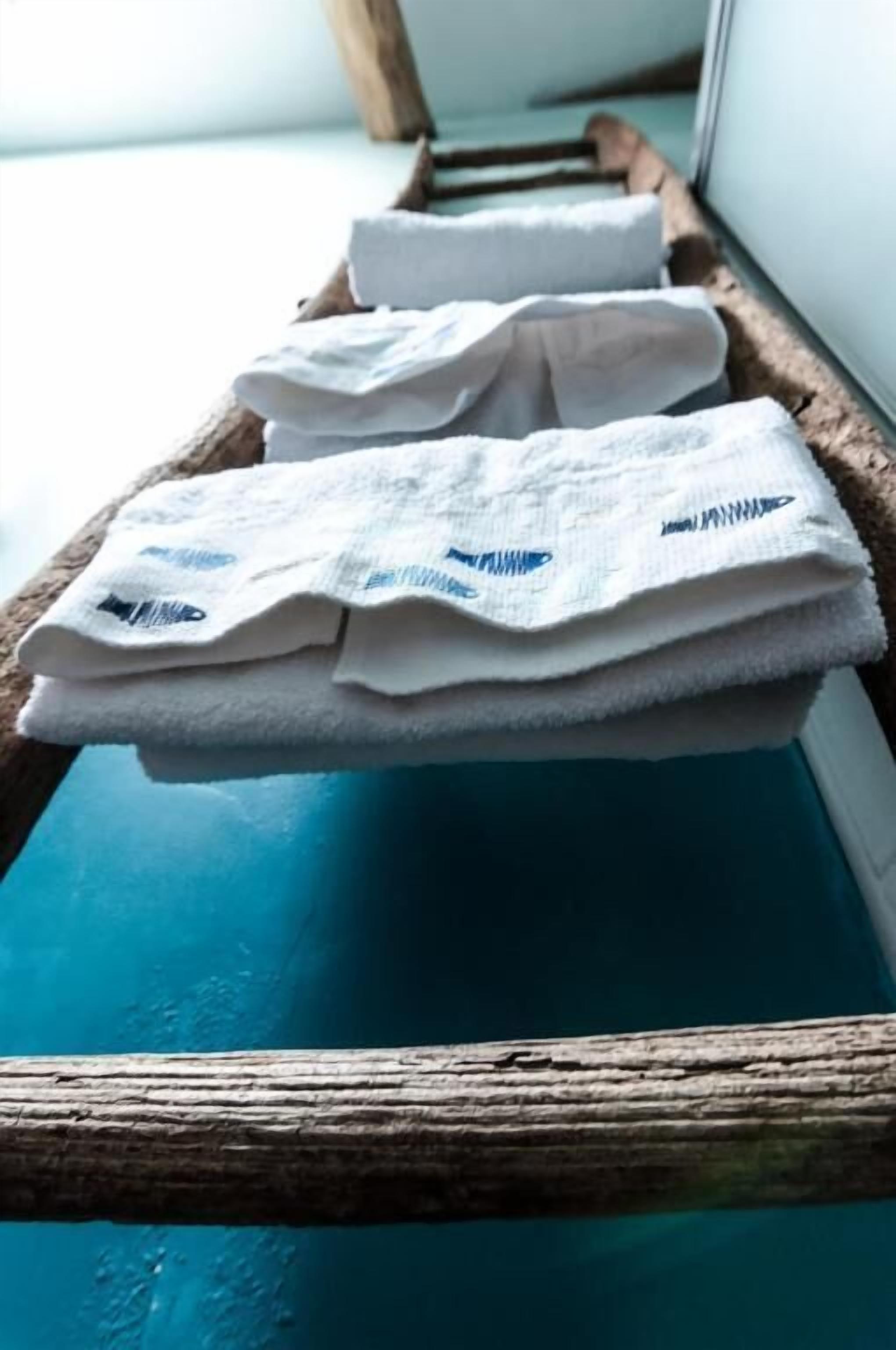 A wooden tray with folded white towels on a blue surface.