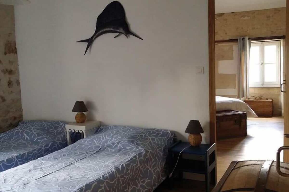 Una habitación con dos camas, una decoración de tiburón en la pared y un cofre de madera.