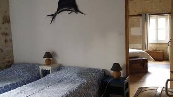 Une chambre avec deux lits, une décoration murale représentant un requin et une malle en bois.