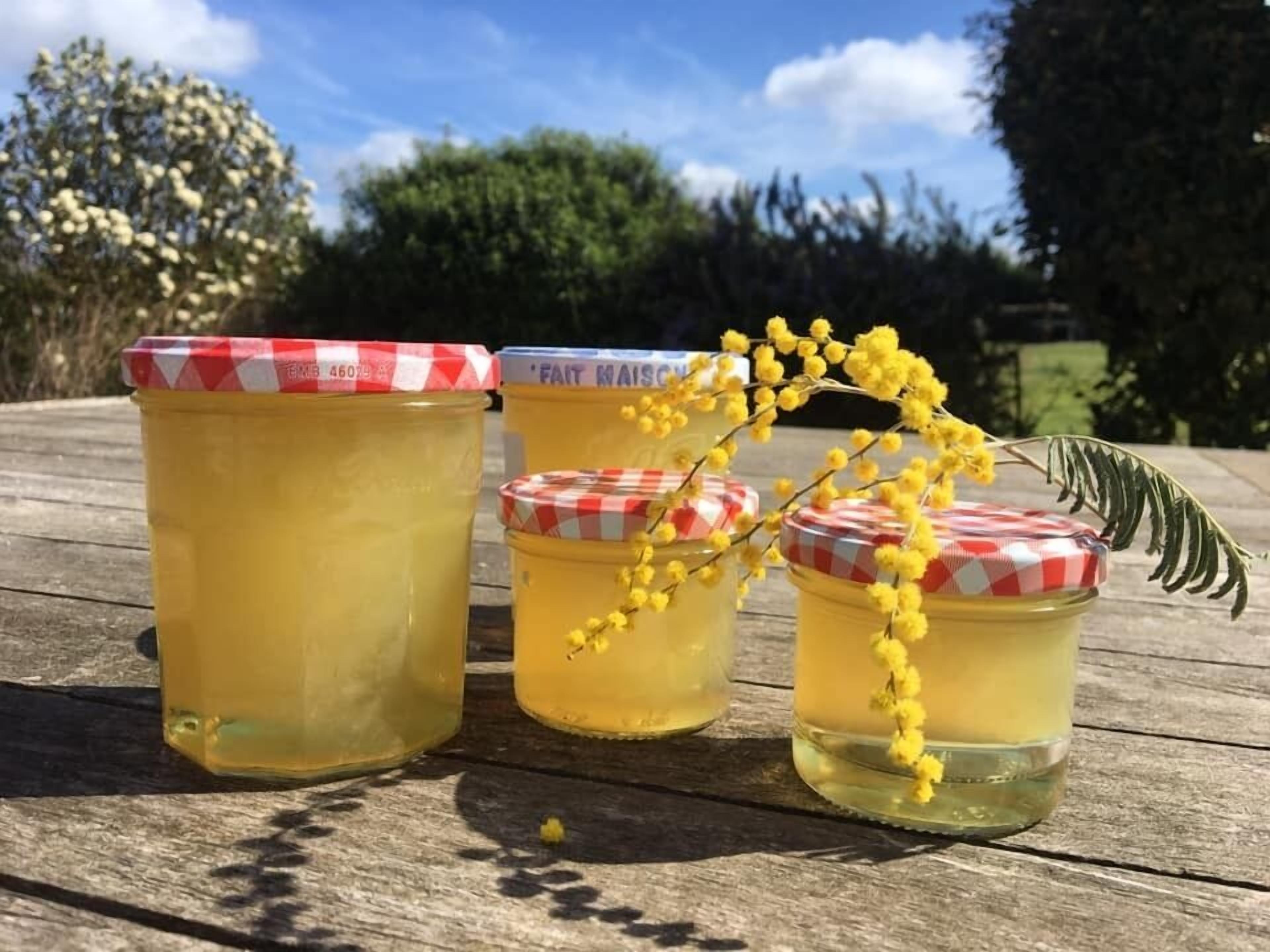 Tres frascos de líquido amarillo con tapas de cuadros sobre una superficie de madera.