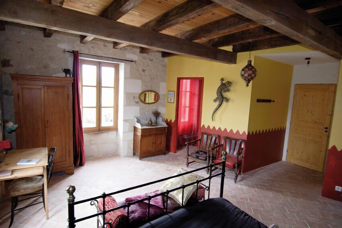 Una habitación rústica con techo de madera, una cama, una mesa de comedor y una puerta roja.