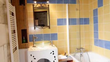 A bathroom with yellow and blue tiles, a white sink with a mirror, a shower, and a towel rack.