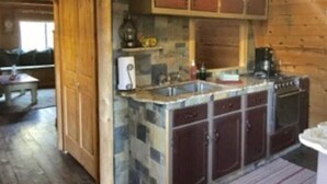 Een rustieke keuken met houten kastjes, een steenschild en een ingebouwde kookplaat.