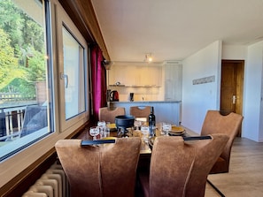 A dining area with a table set for four, a kitchen in the background, and a view of greenery outside. - Magrappé M 647 - SKI LIFT apartment 5 pers (Veysonnaz)