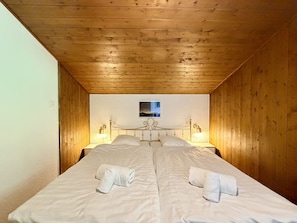 A room with two beds, wooden walls, a small picture on the wall, and two bedside lamps. - Magrappé M 647 - SKI LIFT apartment 5 pers (Veysonnaz)