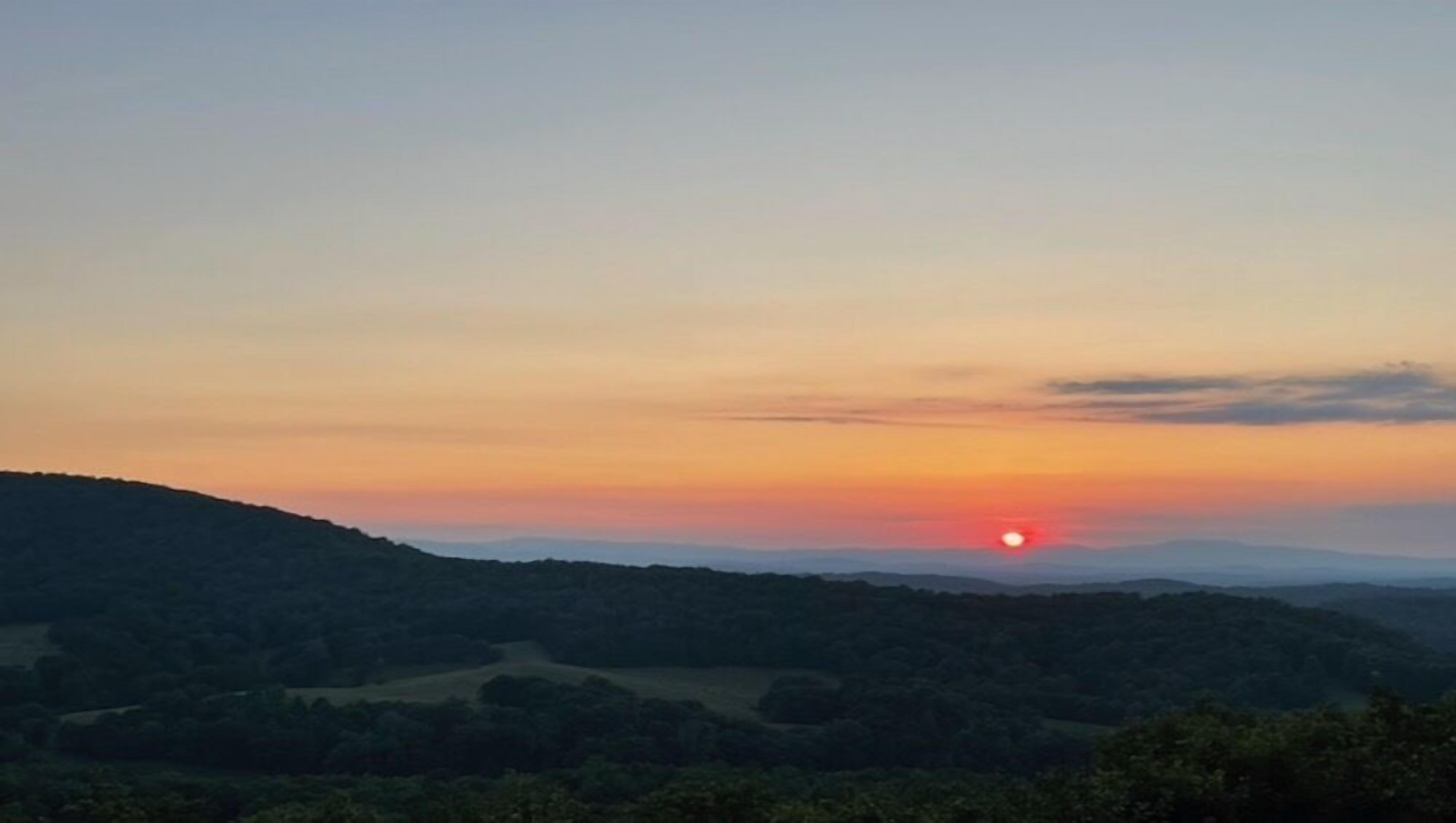 A sunset over a hilly landscape with no visible buildings or structures.
