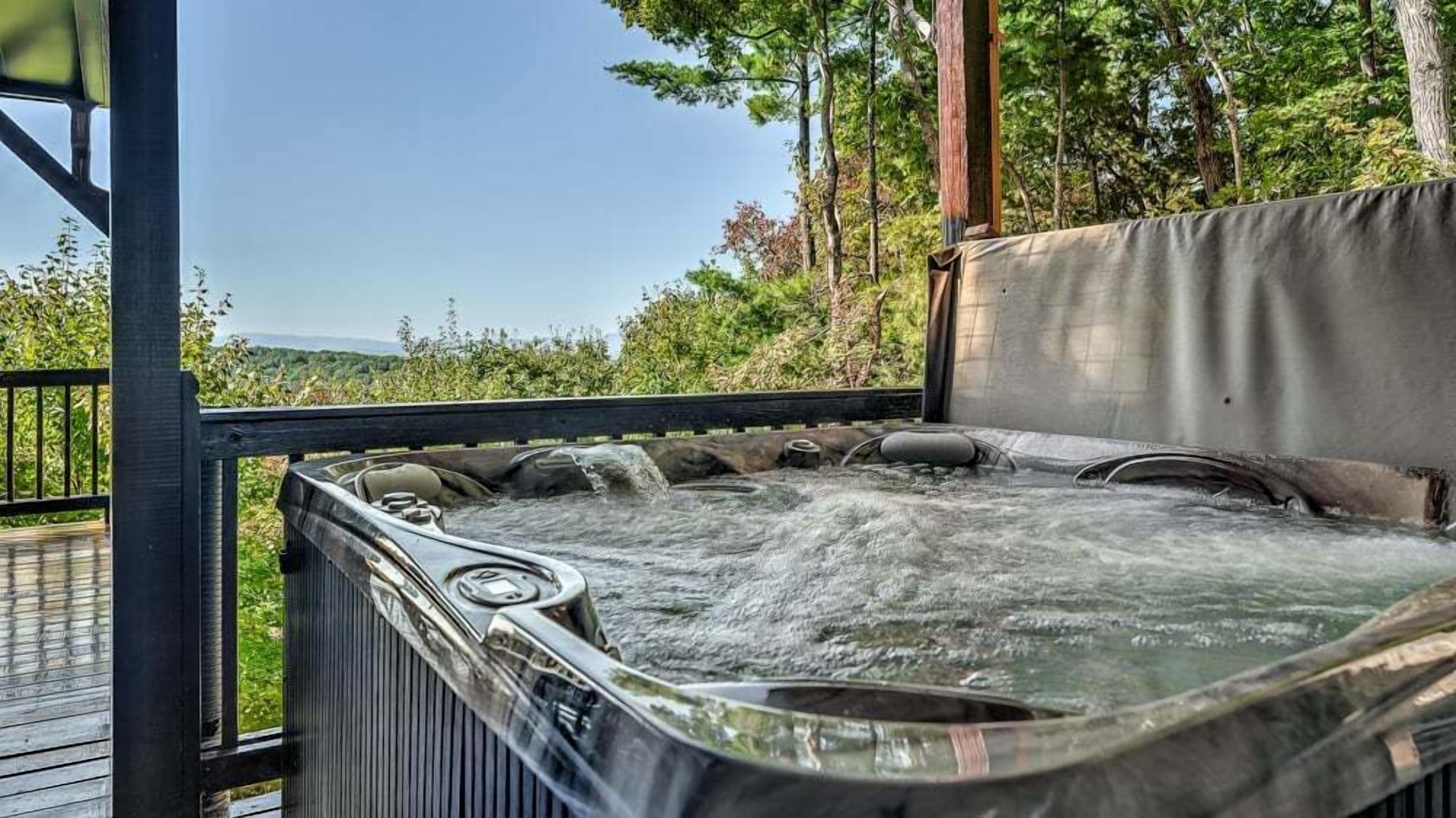A hot tub with a wooden deck and a view of a forested area.