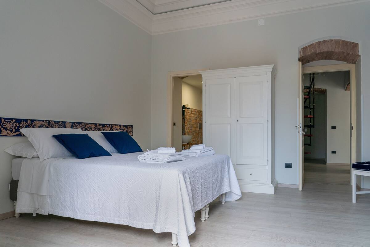 Una camera da letto con un letto, tende bianche e un'armadio.