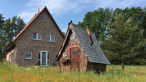 A rustic brick house with a wooden barn-like structure in a field of wildflowers. - Bispinger Heidezauber (Bispingen)