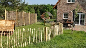 A brick house with a wooden deck, a fenced yard, and a small outdoor table and chairs. - Bispinger Heidezauber (Bispingen)