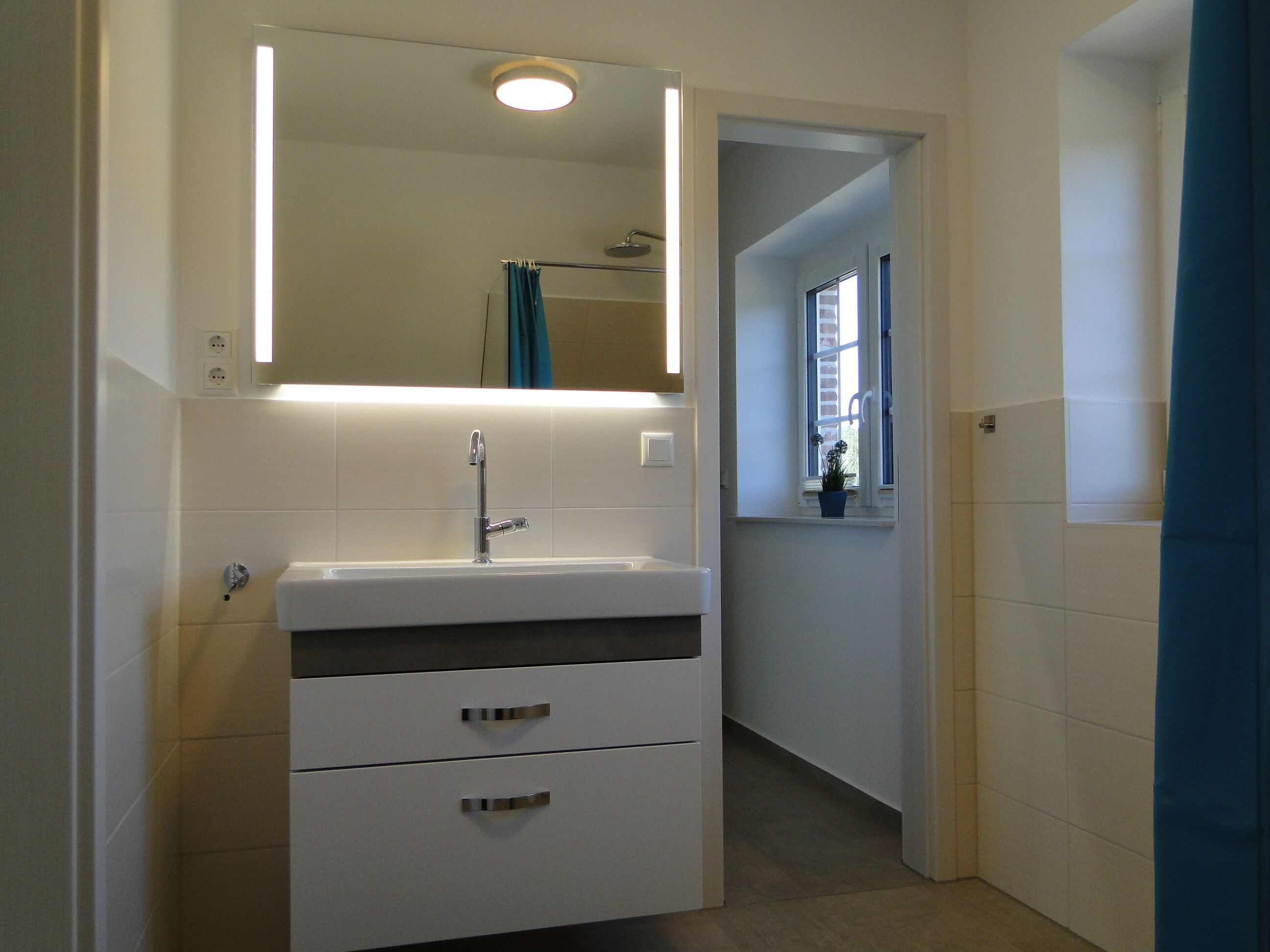 A bathroom with a white sink, a mirror, and a shower.
