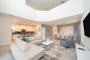 A spacious living area with a sectional sofa, a coffee table, and a TV on a stand.