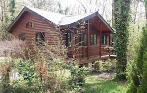 A log cabin with a porch and a small deck.