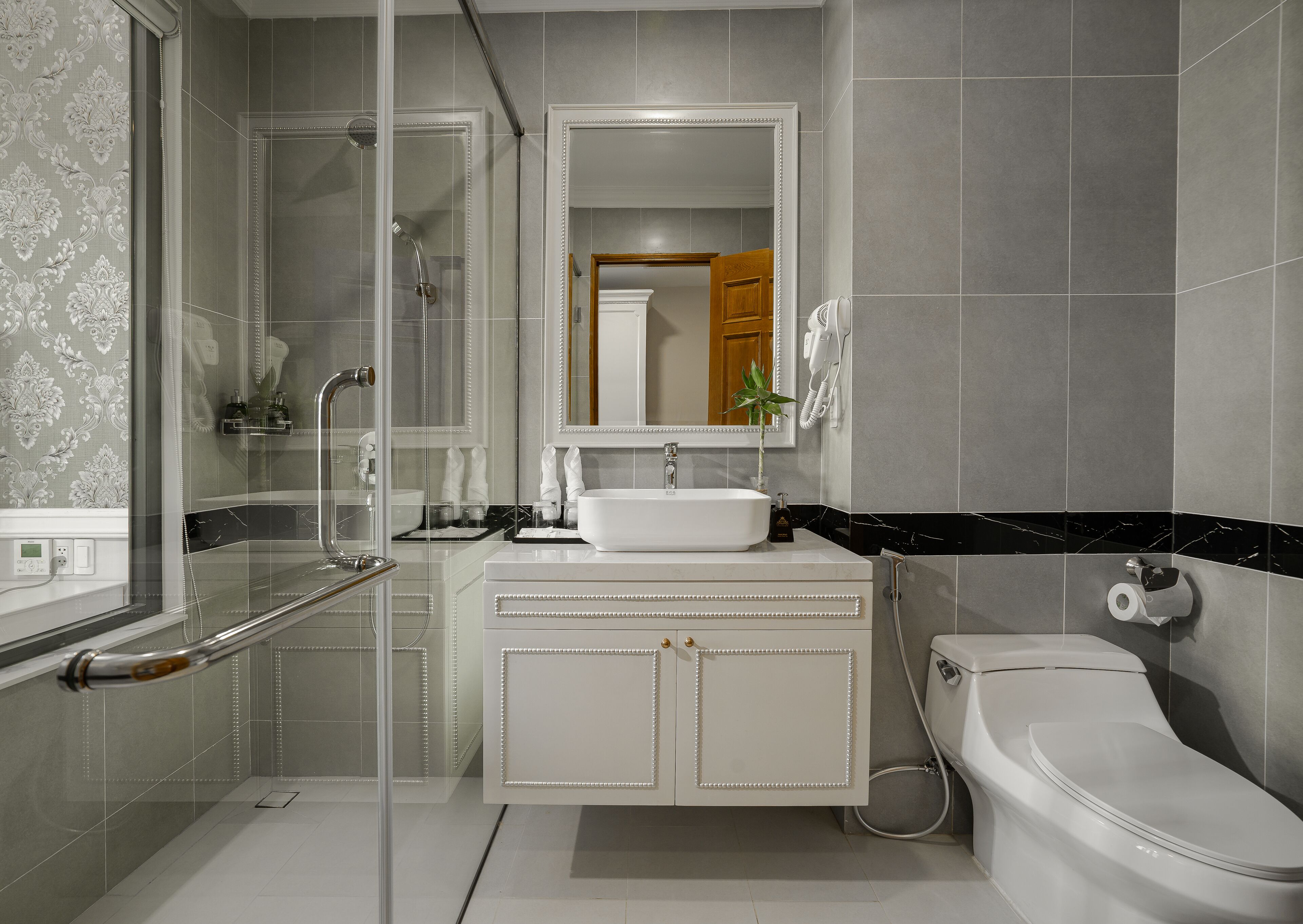 A modern bathroom with a glass shower enclosure, a white sink with a marble countertop, and a toilet.