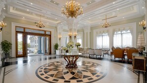 A grand lobby with a central round table, chandeliers, and classical architecture.