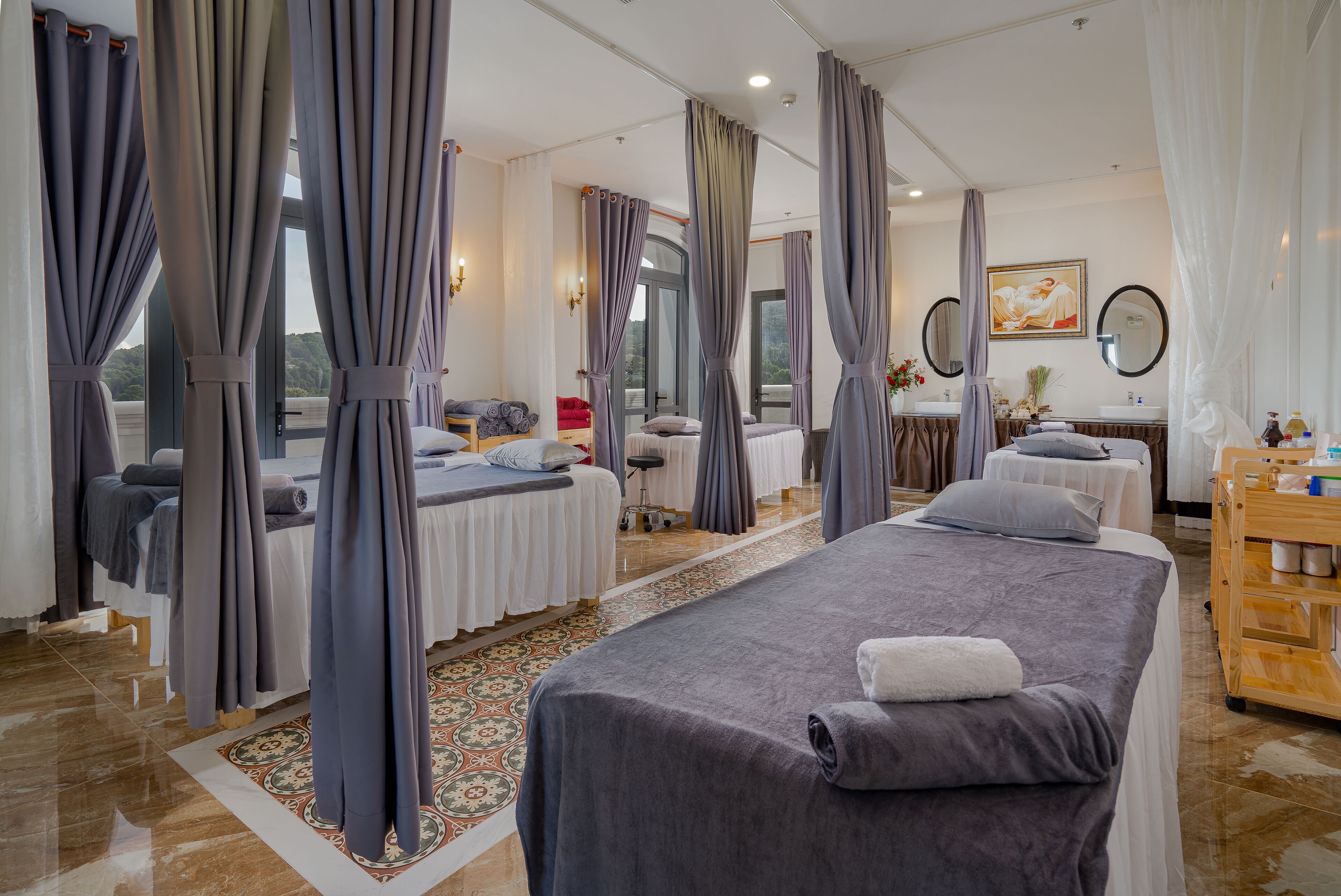 A hotel room with two beds, a sitting area, a vanity with a mirror, and a view of the outdoors.
