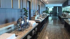 Un hall d’hôtel moderne avec de longs comptoirs de réception, un sol en marbre et des plantes en pot.