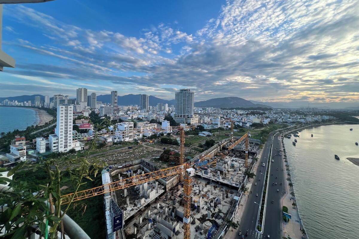 A coastal cityscape with high-rise buildings, a beach, and a construction site.