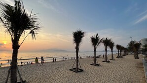Une plage bordée de palmiers où l’on voit des gens se promener.