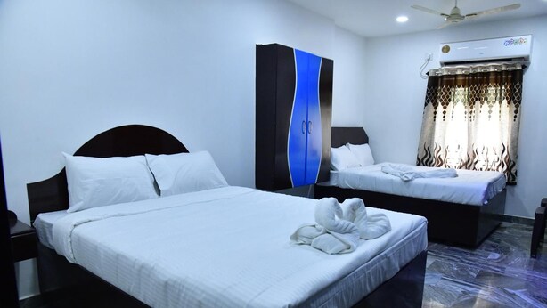 Habitación de hotel con dos camas, un armario, aire acondicionado y ventilador de techo.