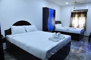 A hotel room with two beds, a wardrobe, an air conditioning unit, and a ceiling fan. - Hotel Jaisas Paradise (Nagercoil)