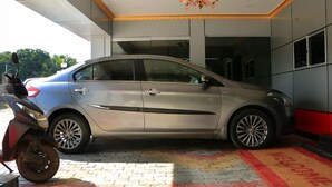 Un sedán plateado estacionado dentro de un edificio con piso de baldosas y una alfombra roja que conduce a la entrada.