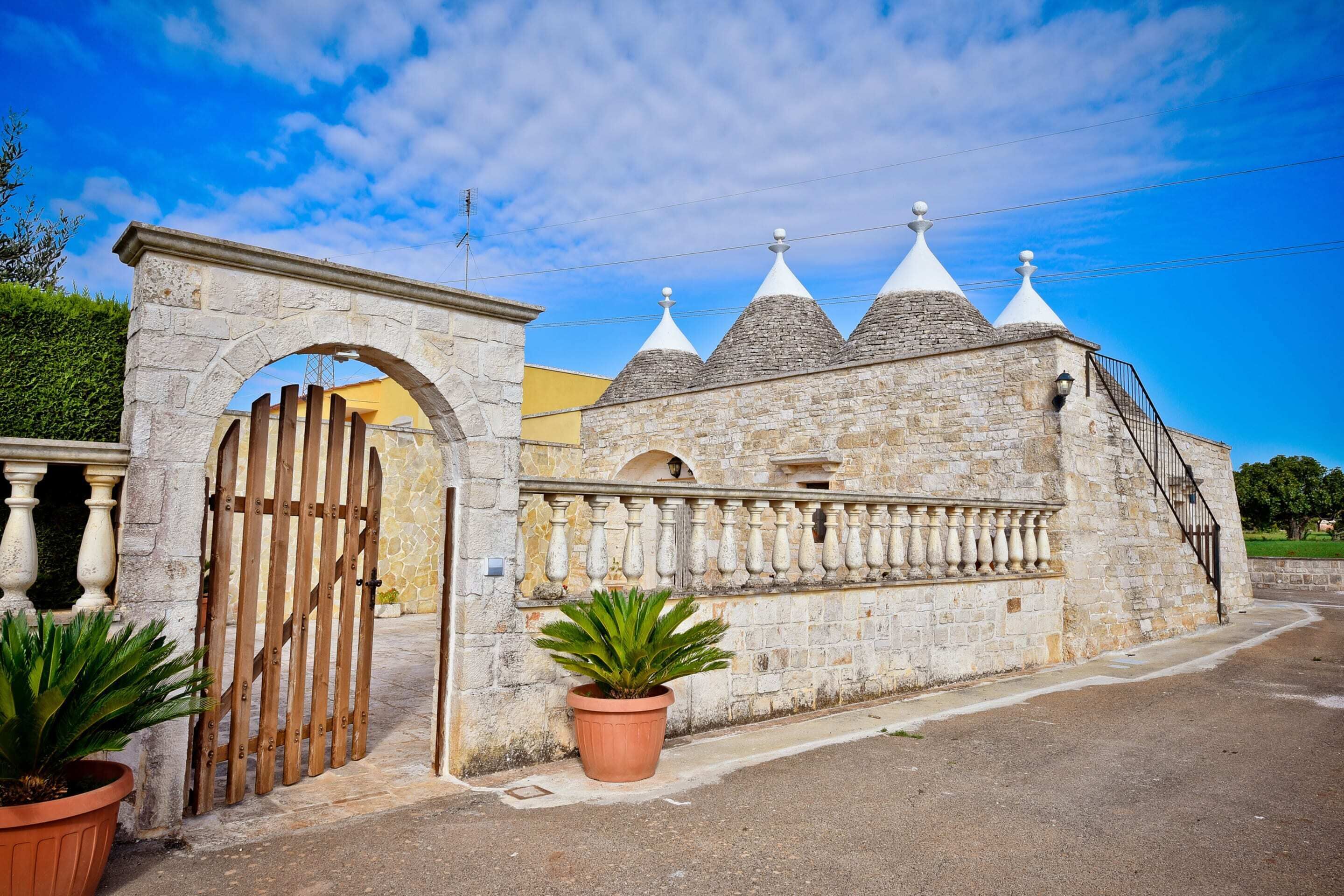 A stone building with a gate, a potted plant, and a clear blue sky.