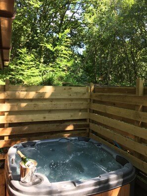 A hot tub in a wooden outdoor area with a view of lush greenery. - Wren 8 Hot Tub (Carmarthen)