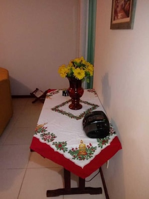 Une table recouverte d’une nappe à motifs floraux, un vase rempli de fleurs jaunes et un casque noir posé sur la table.
