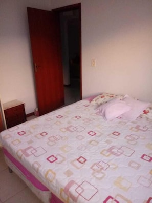 Une chambre à coucher avec un lit, une porte en bois et une petite table de chevet.