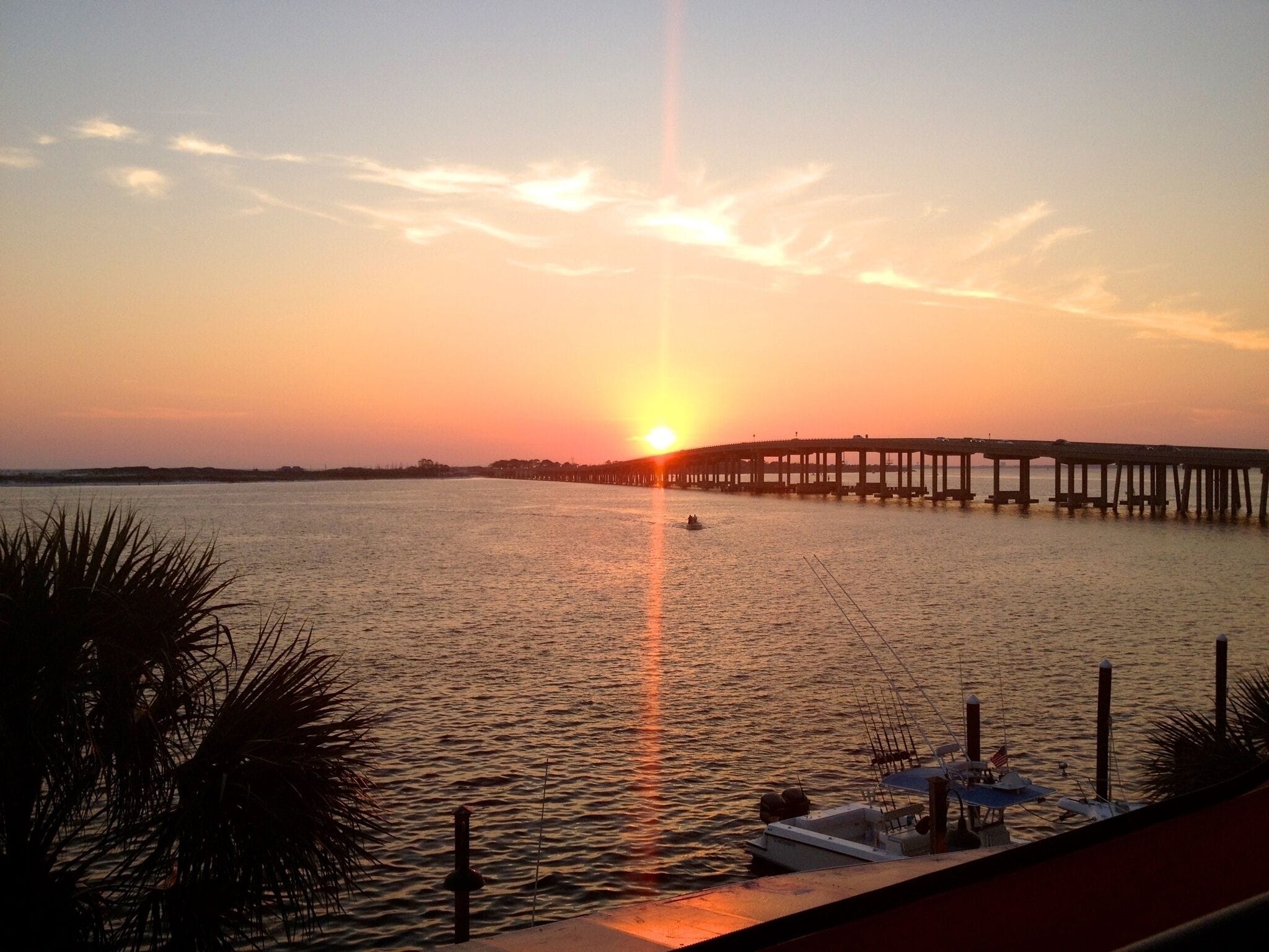 A sunset over a calm body of water with a pier extending into the water.