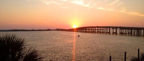 A sunset over a calm body of water with a pier extending into the water.