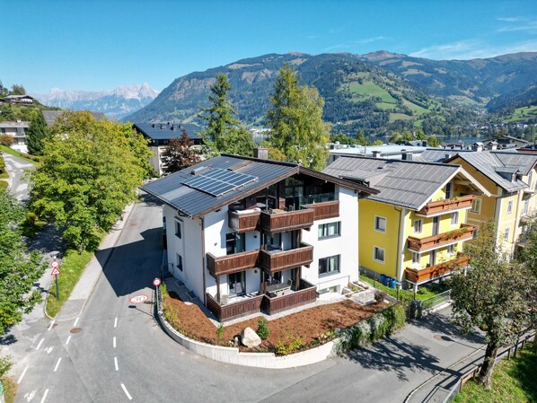 Un edificio moderno con techo de paneles solares, un balcón y vistas de un paisaje montañoso.