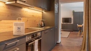 A modern kitchen with stainless steel appliances, wooden cabinetry, and a built-in oven. - Finest Villa Zell am See - Skihaserl (Zell am See)