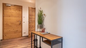 A hallway with wooden doors, a small table with a plant, and a trash bin. - Finest Villa Zell am See - Skihaserl (Zell am See)