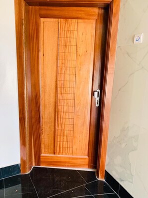 A wooden door with a grid pattern, a silver handle, and a white light switch on the wall.