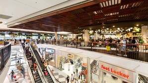 A multi-level shopping mall with escalators, stores, and a wooden ceiling. - Cosy 2-Bed Apartment in the Heart of Strathfield (Strathfield)