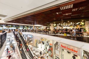 A multi-level shopping mall with escalators, stores, and a wooden ceiling. - Cosy 2-Bed Apartment in the Heart of Strathfield (Strathfield)