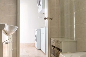 A laundry room with a washing machine, a dryer, and a small cabinet. - Cosy 2-Bed Apartment in the Heart of Strathfield (Strathfield)