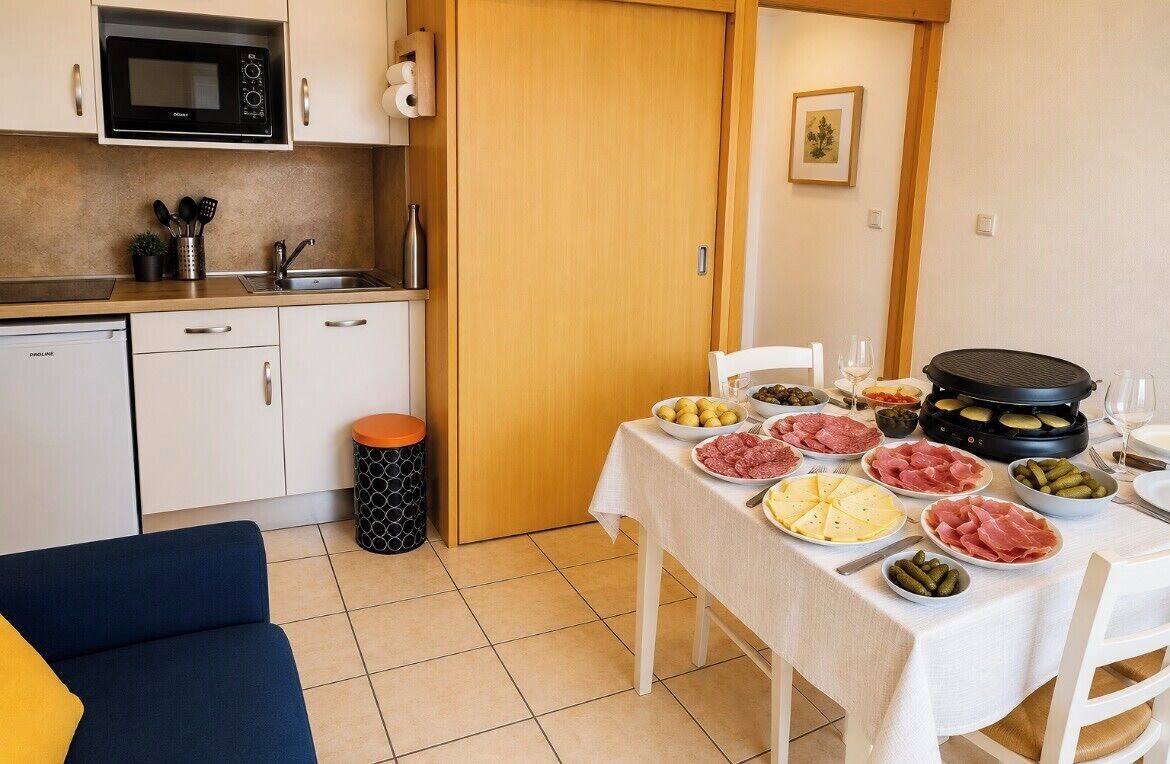 Una cocina compacta con microondas, lavamanos y comedor con mesa dispuesta para una comida.