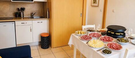 Una cocina compacta con microondas, lavamanos y comedor con mesa dispuesta para una comida.