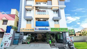 A multi-story building with a flat facade, featuring a ground-level commercial space with signage for a construction company and a hotel. - Rithikha Inn (Chennai)