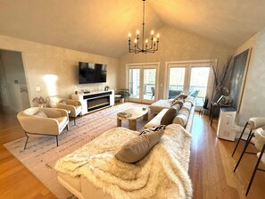 A spacious living room with a fireplace, comfortable seating, and a large TV.