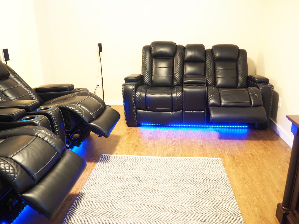 A massage chair with blue LED lights, a wooden floor, and a patterned rug.