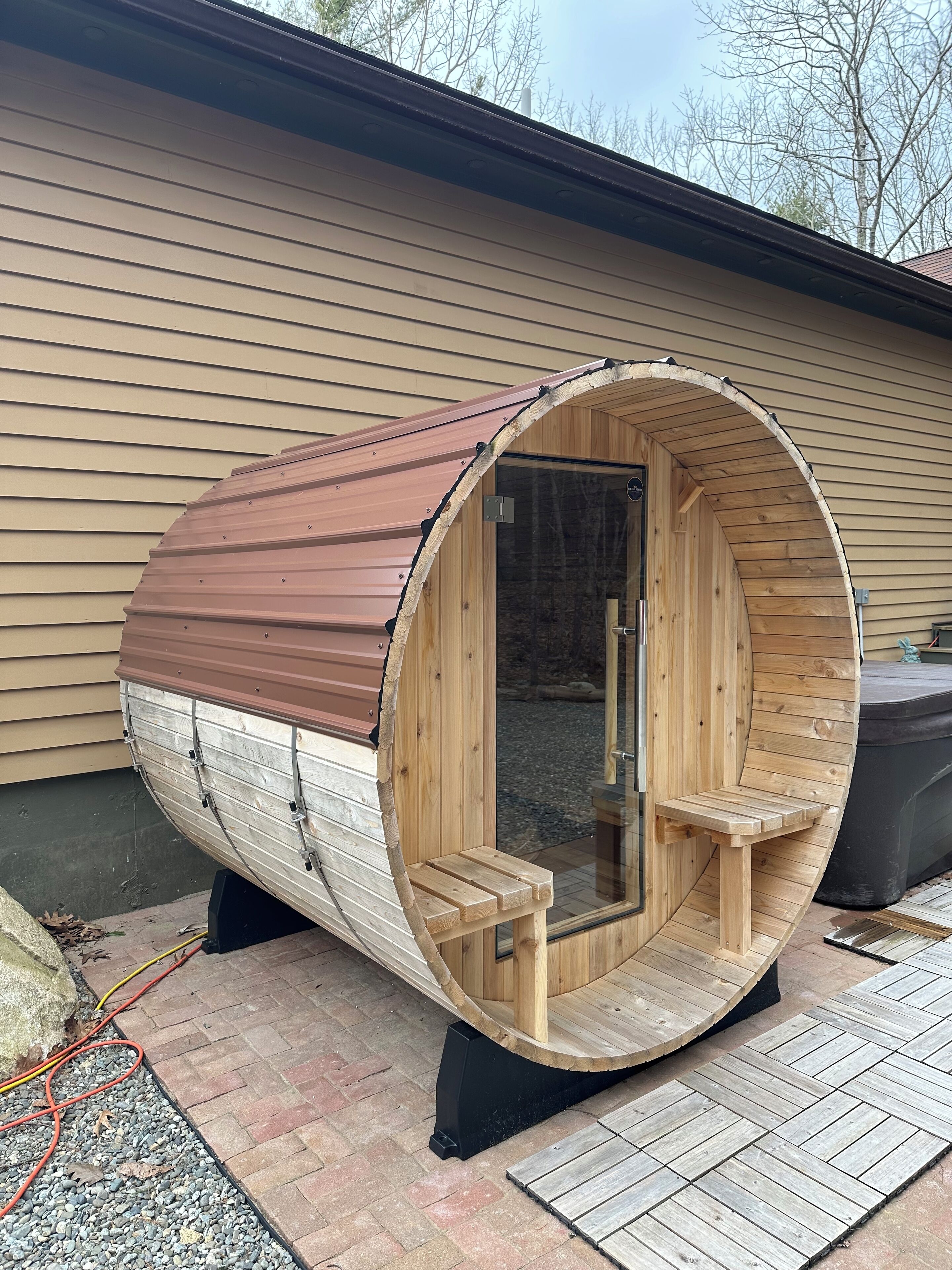 Eine Holzsauna mit gewölbtem Dach, einer Sitzbank im Inneren und einer Glastür.