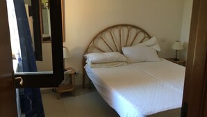 Een slaapkamer met een bed, nachtkastjes, een spiegel en een deur.