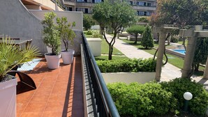 Eine Terrasse mit Blumentöpfen, einem Pool und Blick auf ein Gebäude mit vielen Fenstern.