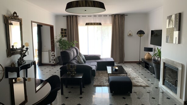Ein modernes Wohnzimmer mit Sofa, Couchtisch und Kamin. Es gibt einen Essbereich mit Tisch und Stühlen, sowie einen großen Spiegel an der Wand.