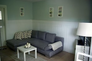 A living room with a grey sofa, a white coffee table with candles, and a lamp.