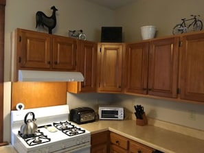 Una cocina con armarios de madera, una estufa a gas, un tostador y un microondas.